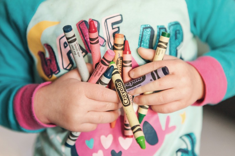 Close-up of child holding crayons